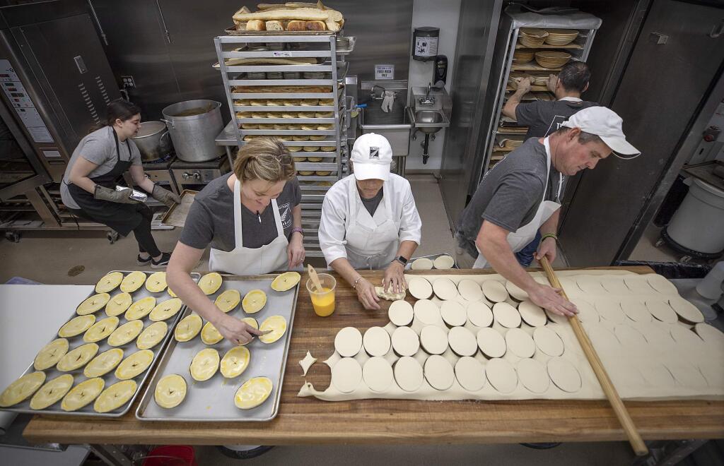 From left, co-owner Bobbi Burton brushes meat pies with egg wash while Suedahlia Byrd and co-owner Warren Burton apply a puff pastry top at BurtoNZ Bakery in Windsor. (photo by John Burgess/The Press Democrat)