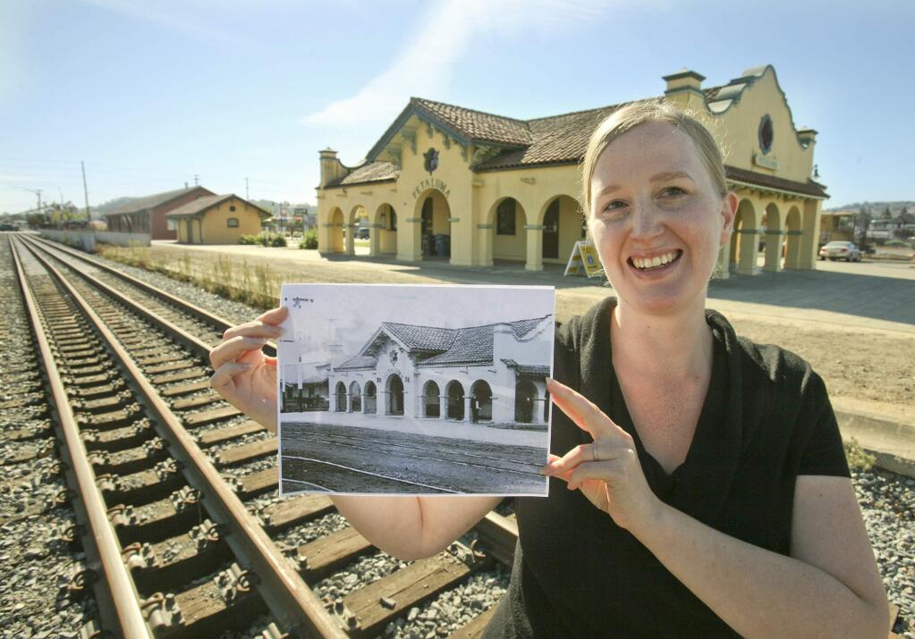 Jenny Hawks, Event and Communications Coordinator for the Petaluma Visitors Center and Downtown Association stands in front of the Petaluma train depot with an historic photo of the depot on Tuesday October 21, 2014 as the train depot is about to have its Centennial Celebration this coming Saturday, October 25th. (SCOTT MANCHESTER/ARGUS-COURIER STAFF)