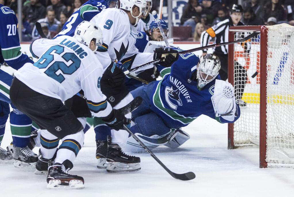 The San Jose Sharks' Kevin Labanc scores against Vancouver Canucks goalie Jacob Markstrom, right, during the first period in Vancouver, B.C., on Saturday. March 17, 2018. (Darryl Dyck/The Canadian Press via AP)