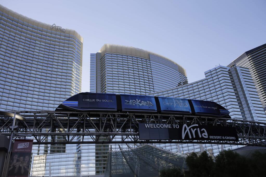 In this Thursday, Aug. 14, 2014 photo, a tram travels by the front of the Aria Resort & Casino, in Las Vegas. This year, hotels will take in a record $2.25 billion in revenue from fees and surcharges, 6 percent more than in 2013 and nearly double that of a decade ago, according to a new study. Nearly half of the increase can be attributed to new surcharges and hotels increasing the amounts of existing fees. (AP Photo/John Locher)