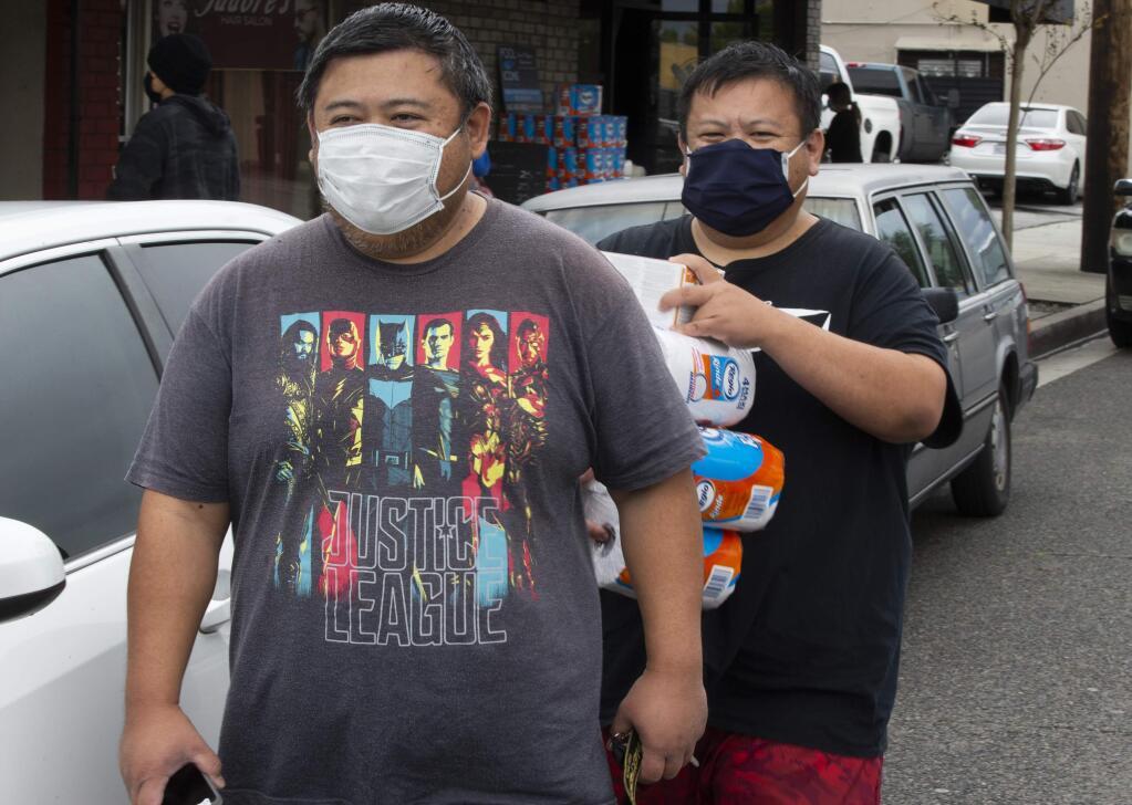 Brothers, Claim Ho, left, and Lee Ho purchase face masks and toilet paper outside Masataco, a taco shop in Whittier, Calif., Tuesday, April 7, 2020. Masataco has managed to sell thousands of face masks at cost, mostly first responders. Just days after recommending that people wear masks to prevent the spread of the coronavirus, a county in Southern California went a step further and ordered all residents to cover their faces when leaving home as the number of infections and deaths continued to rise across California. (AP Photo/Damian Dovarganes)