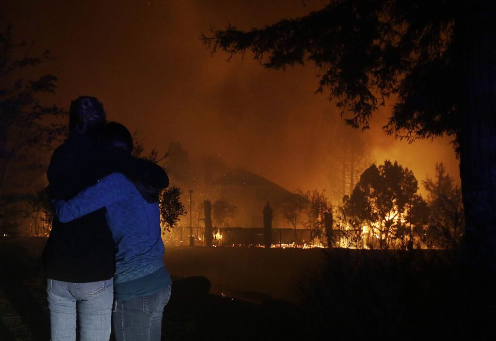 Two women hug as they watch houses burn in Santa Rosa on Monday. (JEFF CHIU / Associated Press)