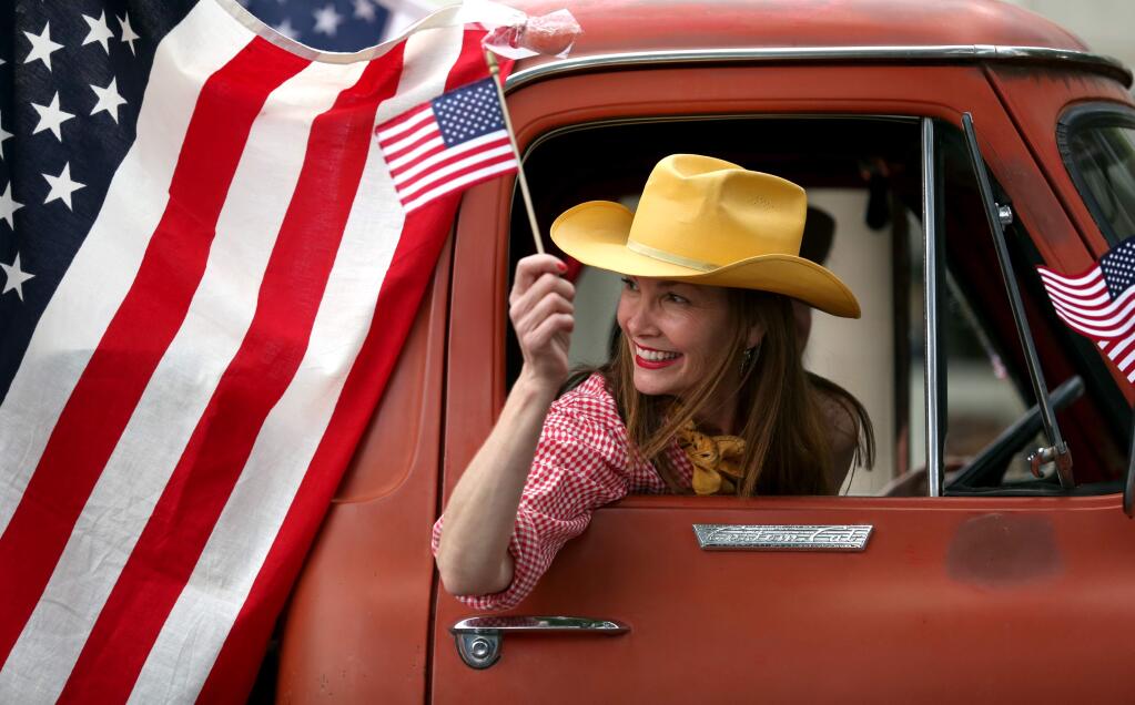 Julie Brown of the Jimtown Store waves a flag during the 66th annual Healdsburg FFA Twilight Parade, Thursday, May 21, 2015. (CRISTA JEREMIASON / The Press Democrat)