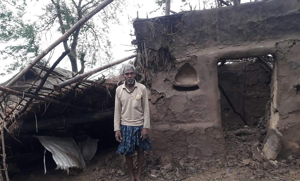 This photo provided by the Indian Red Cross Society shows a villager standing outside his damaged house after Cyclone Amphan, the equivalent of a category 3 hurricane, hit the area in Bhadrak district of Orissa state, India, Thursday, May 21, 2020. A powerful cyclone ripped through densely populated coastal India and Bangladesh, blowing off roofs and whipping up waves that swallowed embankments and bridges and left entire villages without access to fresh water, electricity and communications. At least 24 people were reported killed Thursday. (Indian Red Cross Society via AP)