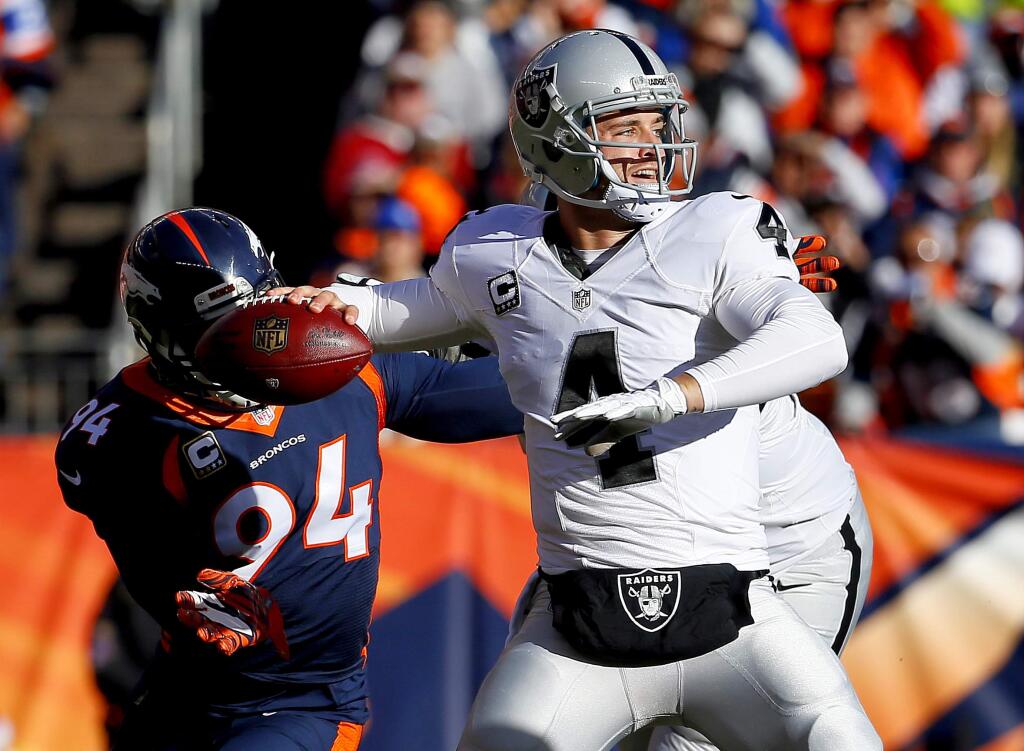 Oakland Raiders quarterback Derek Carr (4) throws under pressure from Denver Broncos outside linebacker DeMarcus Ware (94) during the first half of an NFL football game, Sunday, Dec. 13, 2015, in Denver. (AP Photo/Jack Dempsey)