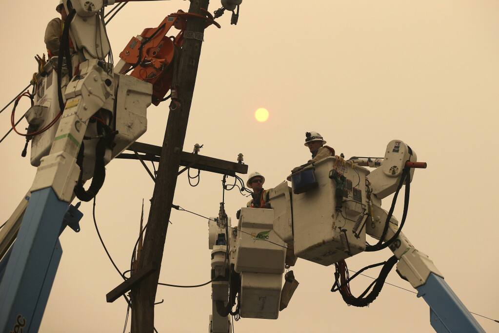 FILE - In this Nov. 9, 2018 file photo, Pacific Gas & Electric crews work to restore power lines in Paradise, Calif. (AP Photo/Rich Pedroncelli, File)