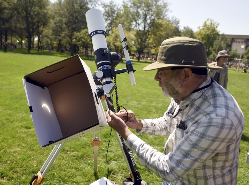 Gilbert Eldredge snaps a quick photo of a projection of the eclipse on Monday, Aug. 21, 2017, on the University of Northern Colorado campus in Greeley, Colo. (Joshua Polson/The Greeley Tribune via AP)