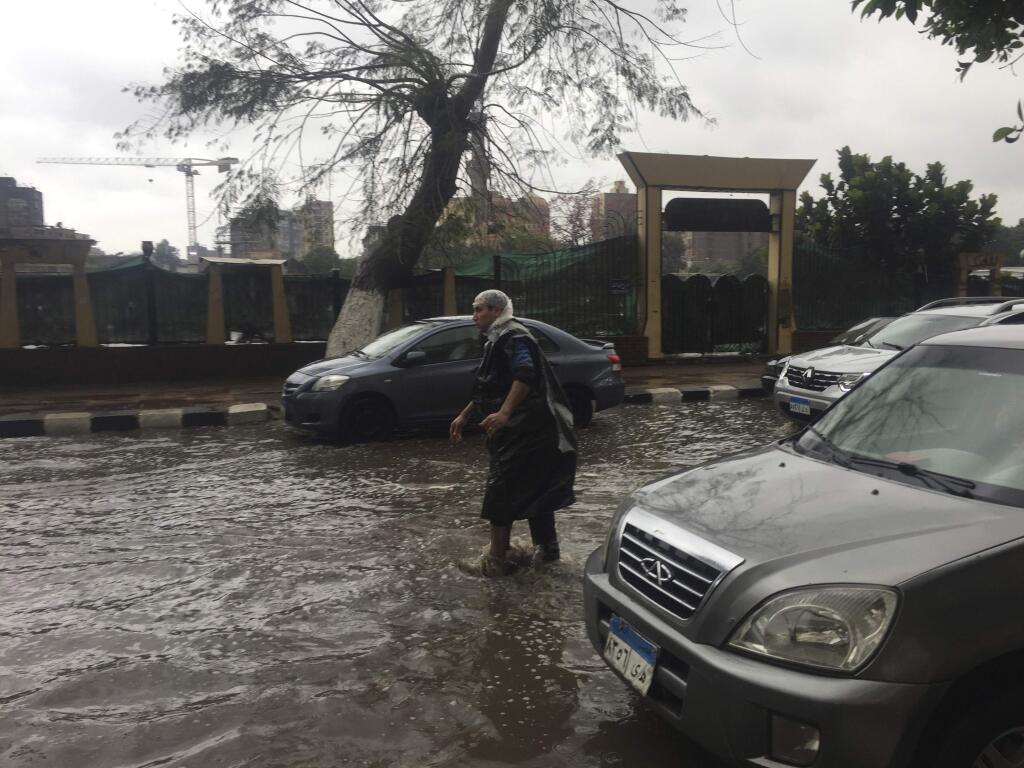 A man wears makeshift rain gear as he navigates a flooded road after heavy rains in the Zamalek district of Cairo, Egypt, Thursday, March 12, 2020. Thunderstorms packing heavy rains and lightning caused widespread flooding in Egypt on Thursday, killing several people and causing authorities to shut down schools and an airport, officials said. (AP Photo/Maya Alleruzzo)