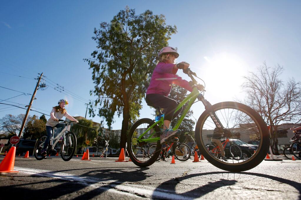 Leah Preuss, 6, right, and other children, whose families lost their homes and belongings in the October wildfires, test their new bicycles on a bike safety course during a free bicycle giveaway for fire survivors at the Trek store in Santa Rosa, California on Saturday, January 6, 2018. (Alvin Jornada / The Press Democrat)