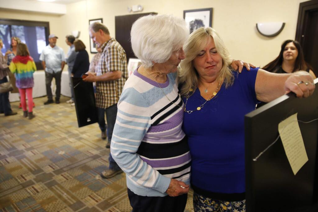Artist Joy Solheim, left, consoles Tubbs fire victim Cindy Lou Williamson, who becomes emotional as she looks at watercolor painting given to her by Solheim at the Best Western Plus Wine Country Inn and Suites on Sunday, April 8, 2018 in Santa Rosa, California . (BETH SCHLANKER/The Press Democrat)