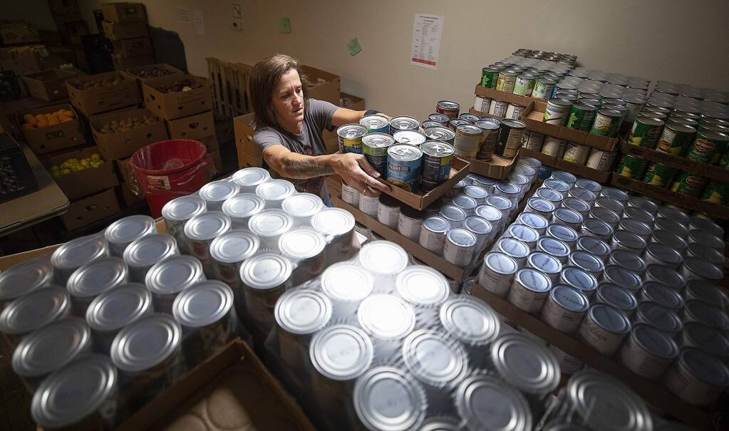 Jennifer Emery sorts and stocks cans of food at the F.I.S.H. Food Pantry in Santa Rosa on Thursday. The independent food pantry distributes over 70,000 pounds of food to nearly 60,000 families in need in Sonoma County. They are hoping to find a new home after learning of a new development at their present location. (photo by John Burgess/The Press Democrat)
