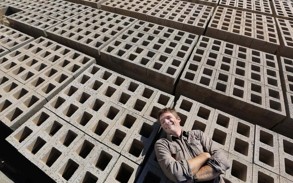 Factory manager Dan Alvarado lays on concrete bricks curing at Watershed Materials of Napa. The bricks use half the cement of standard bricks. (KENT PORTER/ PD)