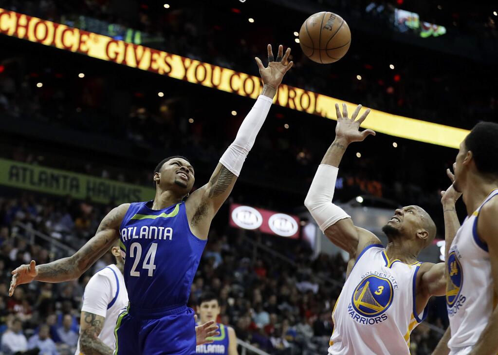 Atlanta Hawks' Kent Bazemore, left, reaches for a ball against Golden State Warriors' David West in the second quarter of an NBA basketball game in Atlanta, Monday, March 6, 2017. (AP Photo/David Goldman)