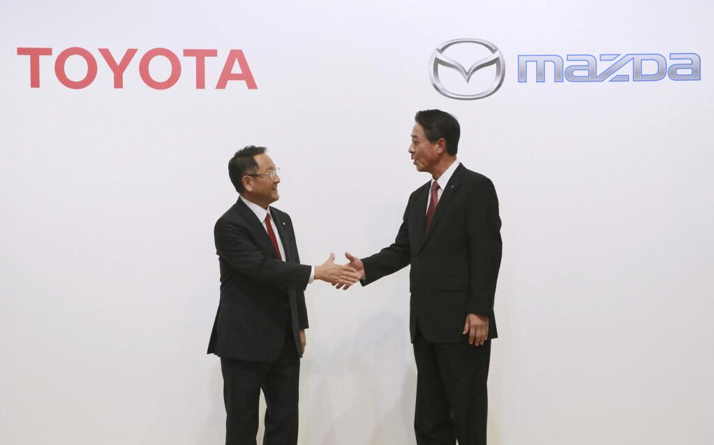 FILE- In this Aug. 4, 2017, file photo, Toyota Motor Corp. President Akio Toyoda, left, and Mazda Motor Corp. President Masamichi Kogai shake hands after a press conference in Tokyo. Japanese automakers Toyota and Mazda have picked Alabama as the site of a new $1.6 billion joint-venture auto manufacturing plant, a person briefed on the decision said Tuesday, Jan. 9, 2018. (AP Photo/Eugene Hoshiko, File)