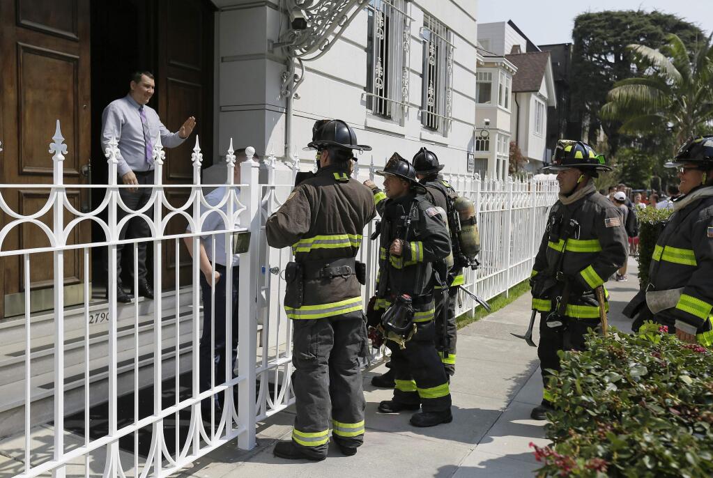 An official at the Consulate-General of Russia tells firemen there is no problem after smoke was seen coming from the rooftop Friday, Sept. 1, 2017, in San Francisco. The U.S. on Thursday ordered Russia to shut its San Francisco consulate and close offices in Washington and New York within 48 hours in response to Russia's decision last month to cut U.S. diplomatic staff in Russia. (AP Photo/Eric Risberg)
