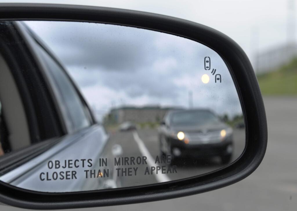 FILE - In his May 22, 2012 file photo, a side mirror warning signal in a Ford Taurus at an automobile testing area in Oxon Hill, Md. Safety systems to prevent cars from drifting into another lane or warn drivers of vehicles in their blind spots are beginning to live up to their potential to significantly reduce crashes, according to two studies released Wednesday, Aug. 23, 2017. (AP Photo/Susan Walsh, File)