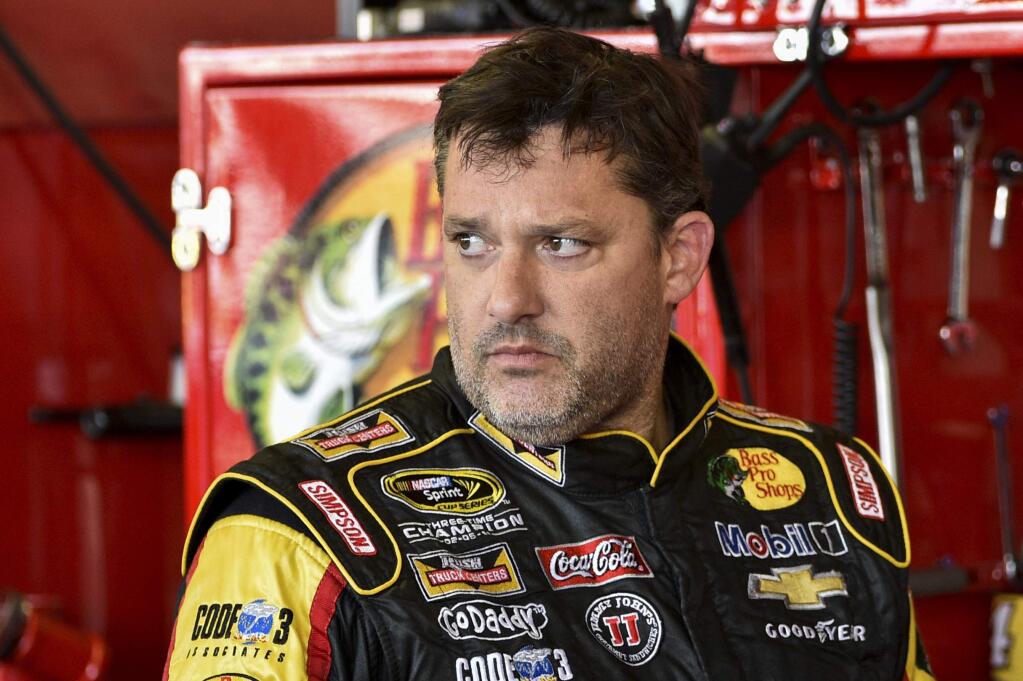 In this Friday, Aug. 8, 2014 photograph, Tony Stewart stands in the garage area after a practice session for Sunday's NASCAR Sprint Cup Series auto race at Watkins Glen International, in Watkins Glen N.Y. (AP Photo/Derik Hamilton)
