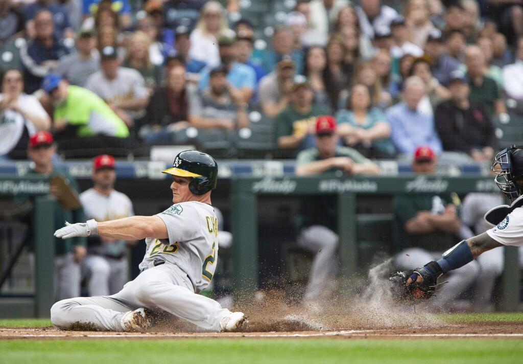The Oakland Athletics' Matt Chapman slides safely into home to score, avoiding the tag by Seattle Mariners catcher Omar Narvaez, during the first inning Saturday, July 6, 2019, in Seattle. (AP Photo/Lindsey Wasson)