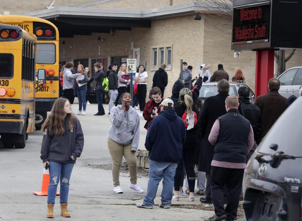 Waukesha South High School students find their waiting parents and friends and hug after they leave the building following shots fired inside the school, Monday, December 2, 2019. A suspect is in custody after a student exchanged gunfire with a school resource officer Monday morning, a spokeswoman for the school district confirmed. (Rick Wood/Milwaukee Journal-Sentinel via AP)