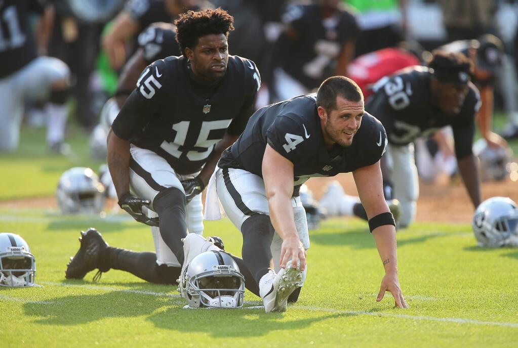 Oakland Raiders quarterback Derek Carr and wide receiver Michael Crabtree stretch before their game against the Los Angeles Rams, in Oakland on Saturday, August 19, 2017. (Christopher Chung/ The Press Democrat)