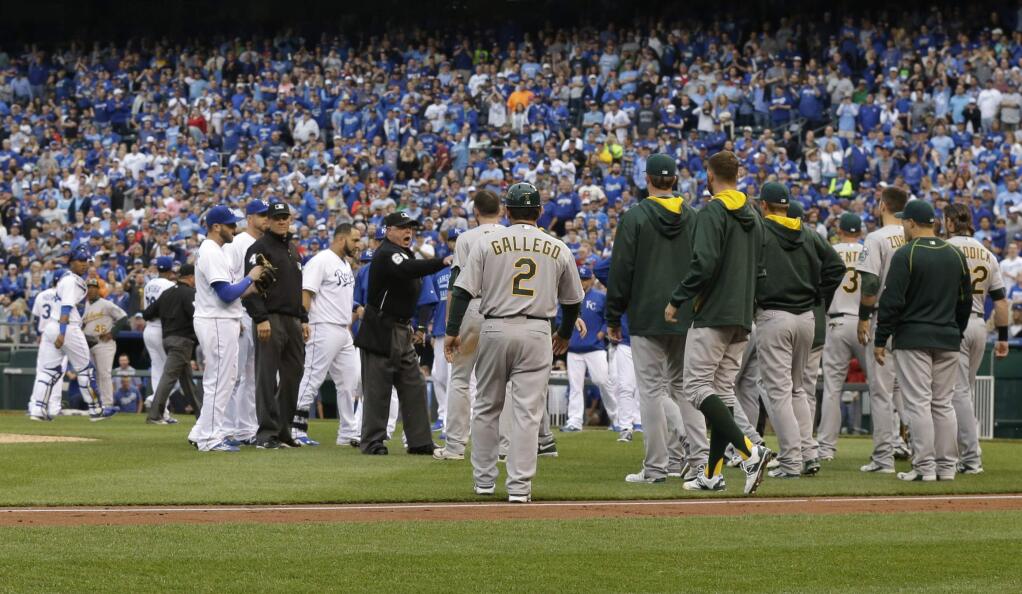 Umpires get between the Oakland Athletics and Kansas City Royals after benches emptied after Oakland Athletics' Brett Lawrie was hit by a pitch during the fourth inning of a baseball game at Kauffman Stadium in Kansas City, Mo., Saturday, April 18, 2015. (AP Photo/Orlin Wagner)