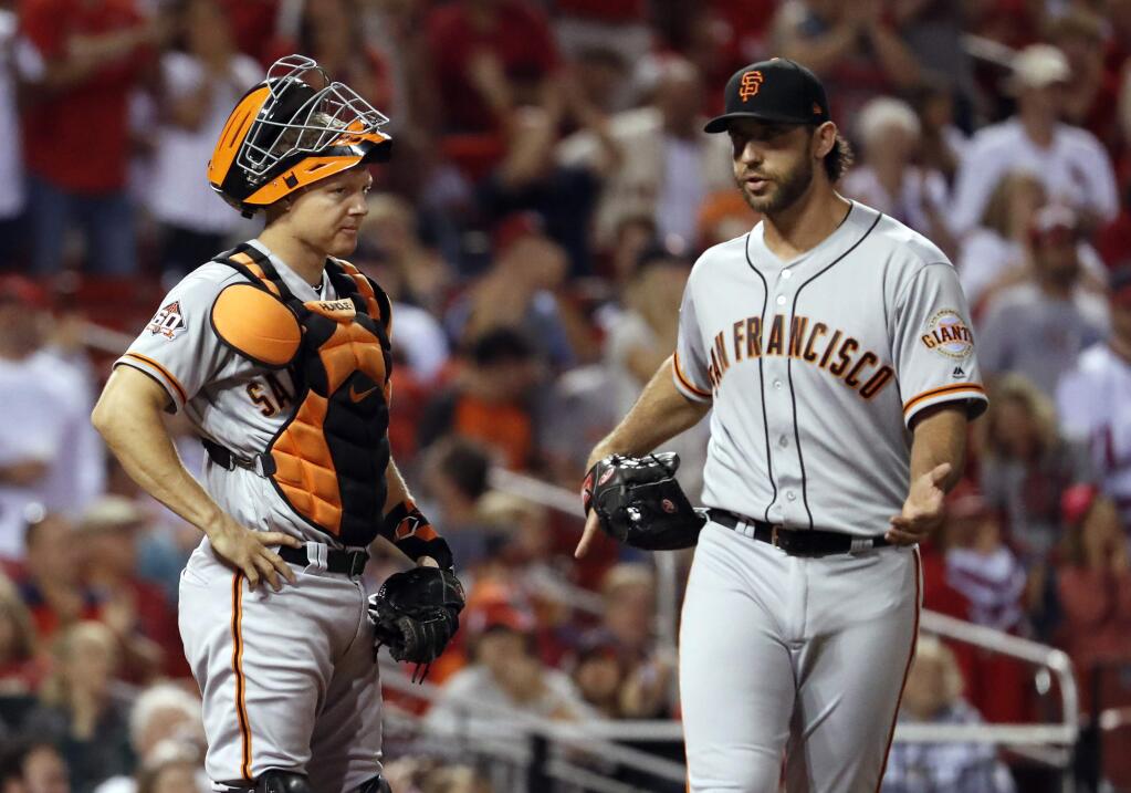 San Francisco Giants catcher Nick Hundley, left, looks at starting pitcher Madison Bumgarner as Bumgarner gestures following a score by the St. Louis Cardinals during the fifth inning of a baseball game Friday, Sept. 21, 2018, in St. Louis. (AP Photo/Jeff Roberson)