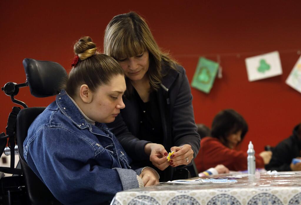 Chrissy Wilka, a resident of Baird House, works on a craft project with the help of Povi Wagner, the administrator, at the Kaleidoscope Adult Day Program in Santa Rosa. (BETH SCHLANKER / The Press Democrat)