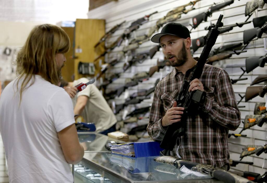 Manager Chris Ostrom talks about the new compliance laws for AR-10 and AR-15 guns with a customer who wished not to give his name at Pacific Outfitters in Ukiah, on Wednesday, December 21, 2016. (BETH SCHLANKER/ The Press Democrat)