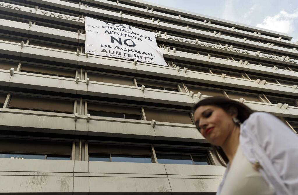A woman passes a banner supporting the NO vote to the upcoming referendum at the Finance Ministry in Athens, Wednesday, July 1, 2015. Greece's government appeared to be caving into demands from its creditors on Wednesday, offering concessions in a desperate attempt to get more aid hours after its bailout program expired. (AP Photo/Daniel Ochoa de Olza)