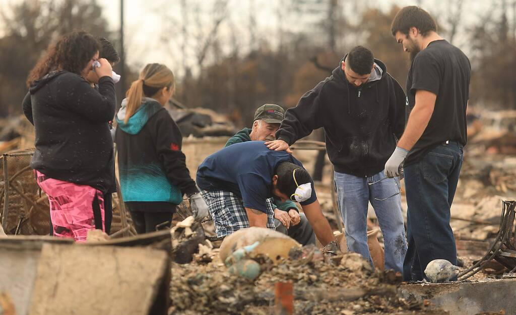 Ben Hernandez, middle, finds their family pet in the ashes of their Hopper Lane home, comforted by his son, Ben jr. with Herenadez's wife Renee, in pink, and the rest of his family, Carlos, Abby, father Ben Sr., in hat, Friday Oct. 20, 2017 in Coffey Park. (Kent Porter / Press Democrat) 2017