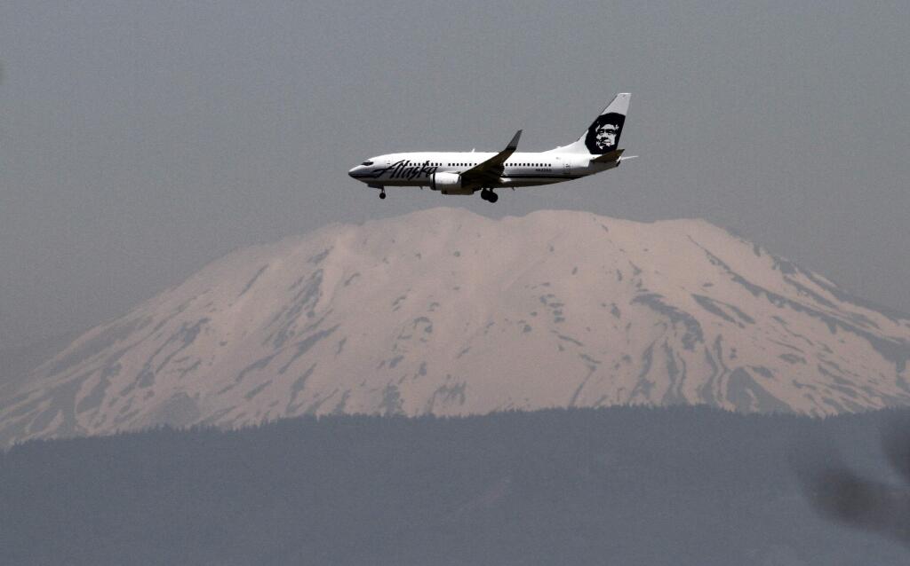 FILE--In this July 9, 2009, file photo, Washington's Mount St. Helens is seen through a layer of smog as an Alaska Airlines plane comes in for a landing at Portland International Airport in Portland, Ore. Alaska Airlines is offering a charter flight off the Oregon coast during the solar eclipse Aug. 21, 2017, that will allow select passengers to view the astronomical event from the sky. The flight will take off at 7:50 a.m. from Portland, Ore., and is by invitation-only for astronomers and other experts. (AP Photo/Don Ryan, file)