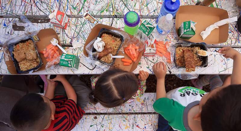 Kent Porter/Press DemocratChildren eat egg rolls and rice with carrots, milk and apple juice from the Redwood Empire Food Bank at Bayer Farm in Santa Rosa in June 2017.