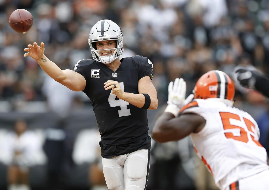 In this Sunday, Sept. 30, 2018, file photo, Oakland Raiders quarterback Derek Carr passes against Cleveland Browns linebacker Genard Avery during overtime in Oakland. Carr is the first player in four years to get sacked at least three times in seven consecutive games but remains on pace for his first career 4,000-yard season. (AP Photo/D. Ross Cameron, File)