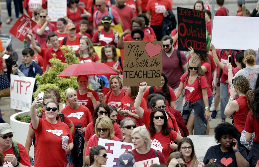 Participants make their way towards the Legislative Building during a teachers rally at the General Assembly in Raleigh, N.C., Wednesday, May 16, 2018. Thousands of teachers rallied the state capital seeking a political showdown over wages and funding for public school classrooms. (AP Photo/Gerry Broome)