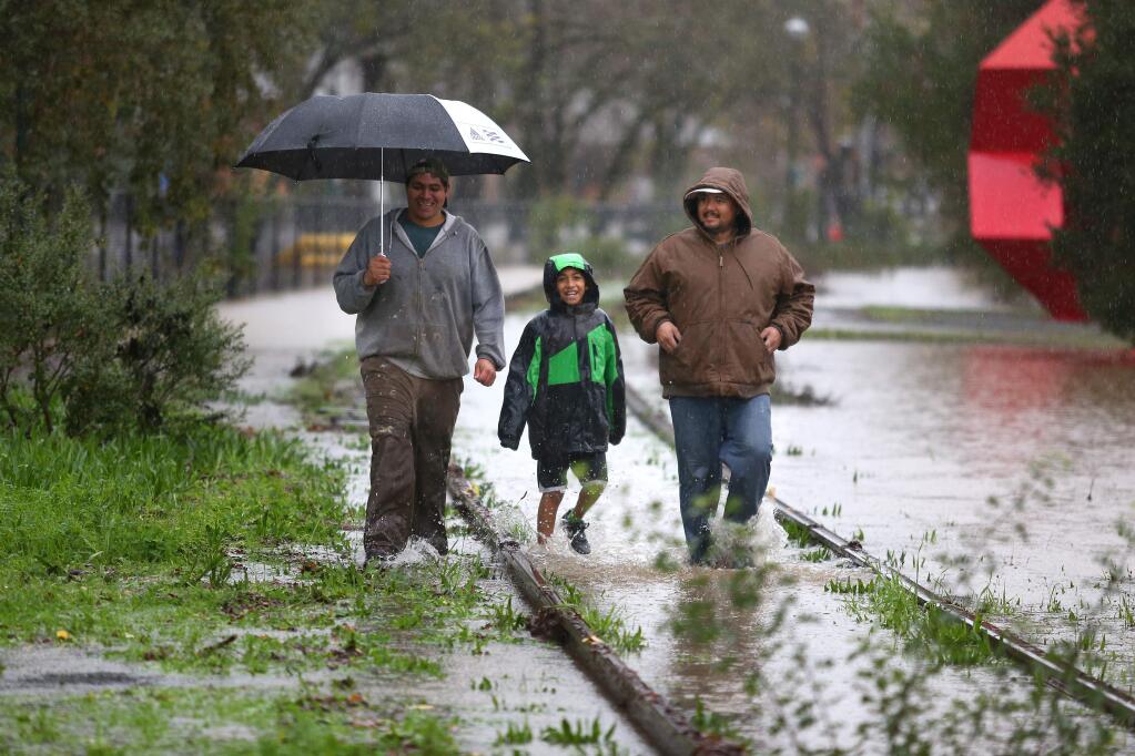 Jose, left, and Adrian Rodriguez, 12, and Manuel Ceja walk along the railroad tracks, parallel to the flooded Foss Creek Pathway, in Healdsburg on Thursday, Dec. 11, 2014.(CHRISTOPHER CHUNG/ PD)