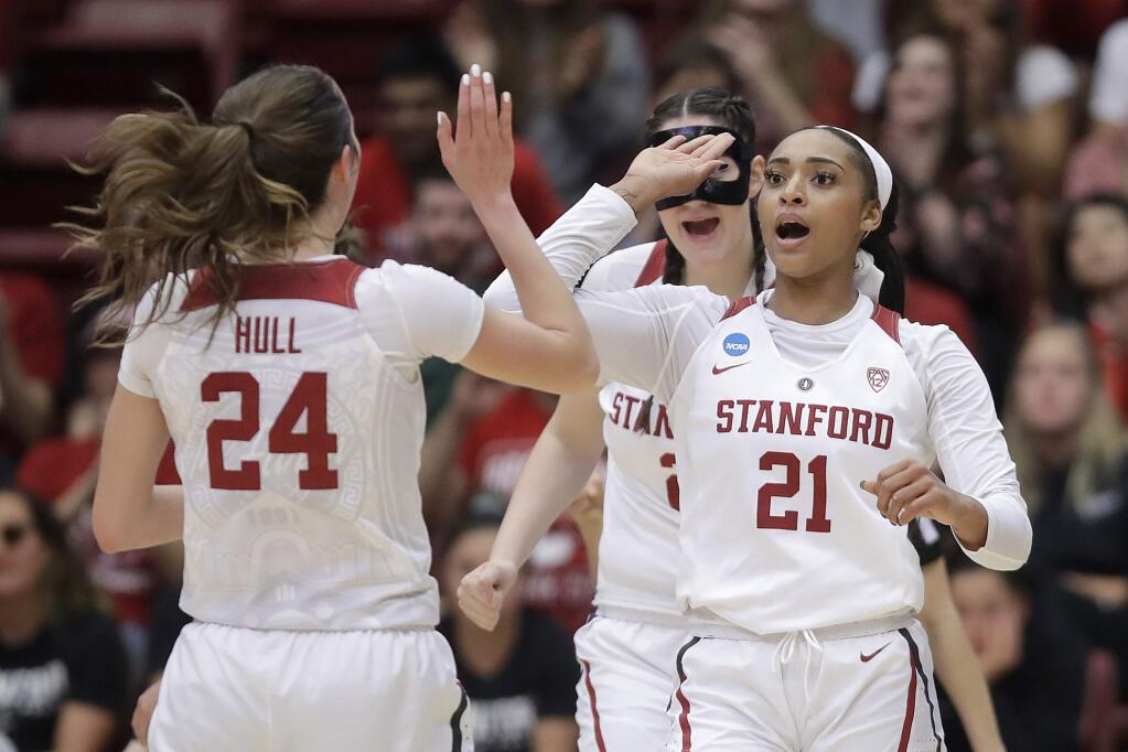 Stanford guard DiJonai Carrington (21) celebrates with forward Lacie Hull (24) and center Shannon Coffee, rear, after scoring against UC Davis during the first half of a first-round game in the NCAA women's college basketball tournament in Stanford, Calif., Saturday, March 23, 2019. (AP Photo/Jeff Chiu)