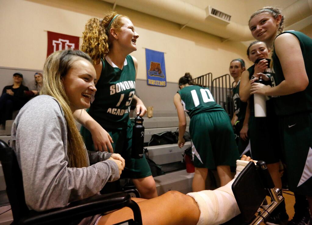 Injured Sonoma Academy basketball player Chloe Colbert, left, laughs with teammates Sonoma Bates (13), and Lauren Reed (33), right, after they defeated Roseland University Prep in Santa Rosa, California on Tuesday, January 26, 2016. (Alvin Jornada / The Press Democrat)