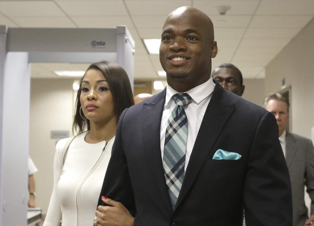 FILE - In this Nov. 4, 2014, file photo, Minnesota Vikings running back Adrian Peterson leaves the courthouse with his wife Ashley Brown Peterson in Conroe, Texas. The NFL has reinstated Minnesota Vikings running back Adrian Peterson, clearing the way for him to return after missing most of last season while facing child abuse charges in Texas. The league announced its decision on Thursday. (AP Photo/Pat Sullivan, File)