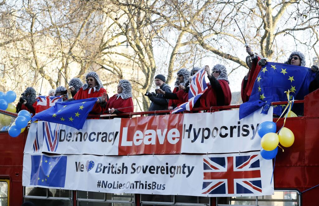 Demonstrators dressed in costume wave flags from the top of a bus outside The Supreme Court in London, Monday, Dec. 5, 2016. May's government will ask Supreme Court justices to overturn a ruling that Parliament must hold a vote before Britain's exit negotiations can begin _ a case that has raised a constitutional quandary and inflamed the country's heated debate about Brexit. (AP Photo/Kirsty Wigglesworth)