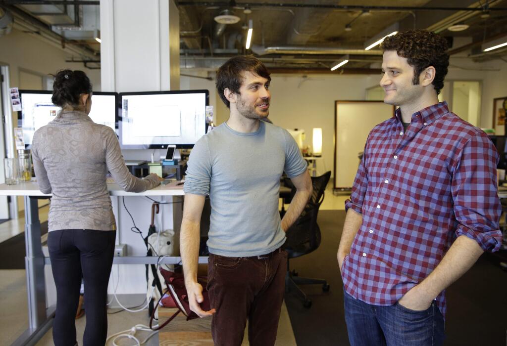 In this photo taken Thursday, April 3, 2014, Asana co-founders Justin Rosenstein, center, and Dustin Moskovitz, right, pose for photos at the company's headquarters in San Francisco. (AP Photo/Eric Risberg)