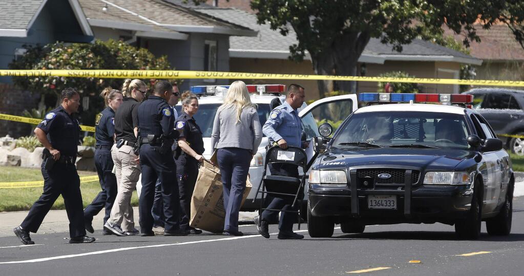 A Sacramento City Police officer, center, carries a bag that was brought from the home where four people were found dead, Thursday, March 23, 2017, in Sacramento, Calif. A suspect is being held in San Francisco. Police are not saying how the four were killed and are not identifying the victims, including their genders and ages. (AP Photo/Rich Pedroncelli)