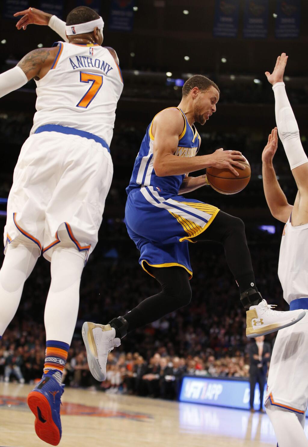 Golden State Warriors guard Stephen Curry (30) jumps through two New York Knicks defenders, including Carmelo Anthony (7), in the first half of an NBA basketball game at Madison Square Garden in New York, Sunday, March 5, 2017. (AP Photo/Kathy Willens)