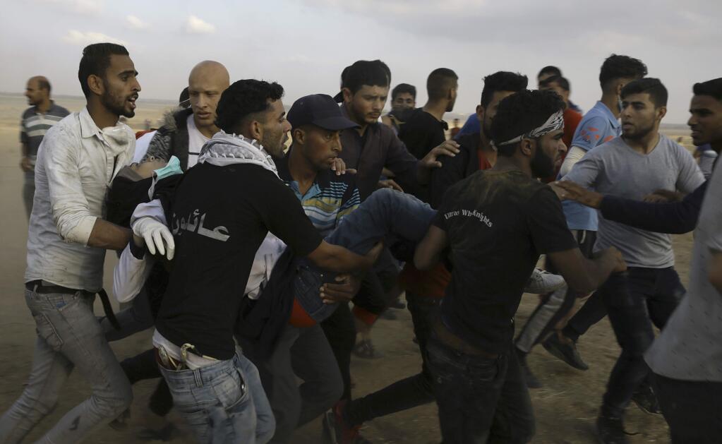 Palestinian protesters evacuate a female medic of Razan Najjar, 21, youth near the Gaza Strip's border with Israel, during a protest east of Khan Younis, Gaza Strip, Friday, June 1, 2018. Najjar, was shot in the chest and died later at hospital, the Health Ministry said. (AP Photo/Adel Hana)