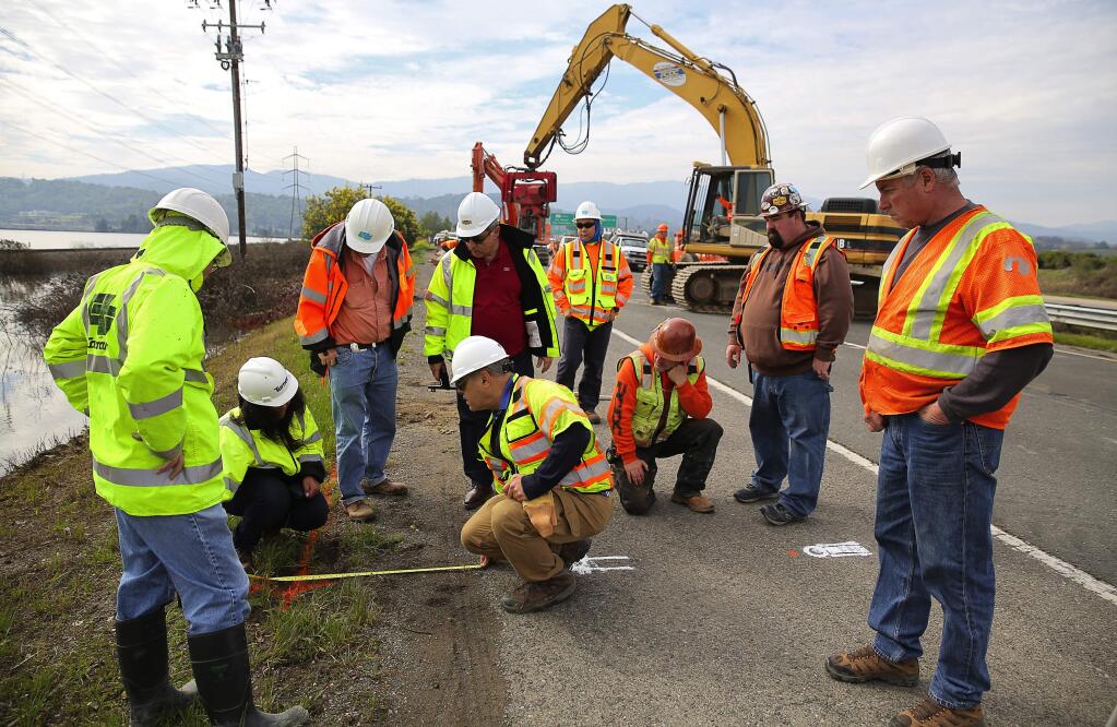 Caltrans engineers take measurements along the shoulder of Highway 37, east of Novato, as work begins to shore up the roadway on Wednesday, February 15, 2017. (Christopher Chung/ The Press Democrat)