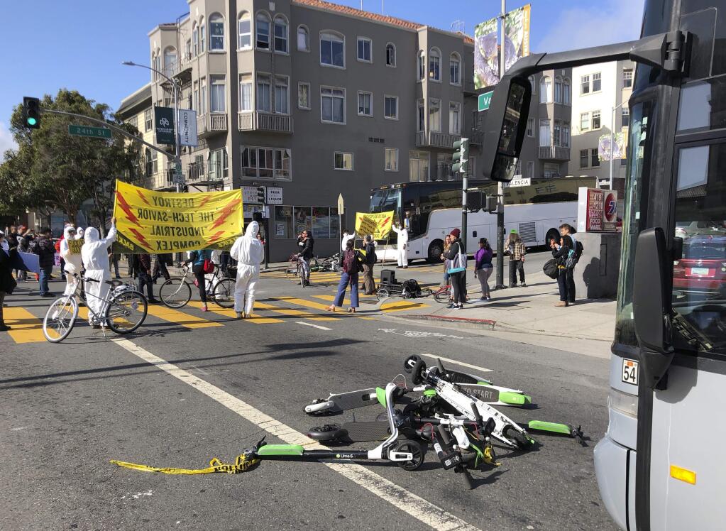 A group of tenants-rights activists block commuter tech buses in the Mission District with motorized scooters during a protest Thursday, May 31, 2018, in San Francisco. Nearly 60 tenants-rights activists blocked commuter tech buses in San Francisco's Mission District with motorized scooters, claiming that city officials treat “shared” scooters better than homeless. The San Francisco Examiner reports that protesters Thursday morning piled more than a dozen of the e-scooters at an intersection and blocked at least nine buses headed for Silicon Valley. (AP Photo/Richard Jacobsen)