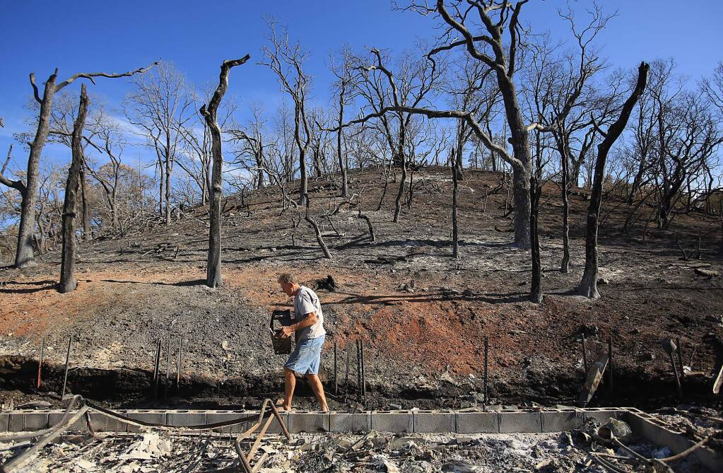 Bill Hilbrandie carries off his sisters computer hard drive from the remains of her home, destroyed by the Rocky Fire in Lake County, Tuesday Sept. 1, 2015. (Kent Porter / Press Democrat) 2015
