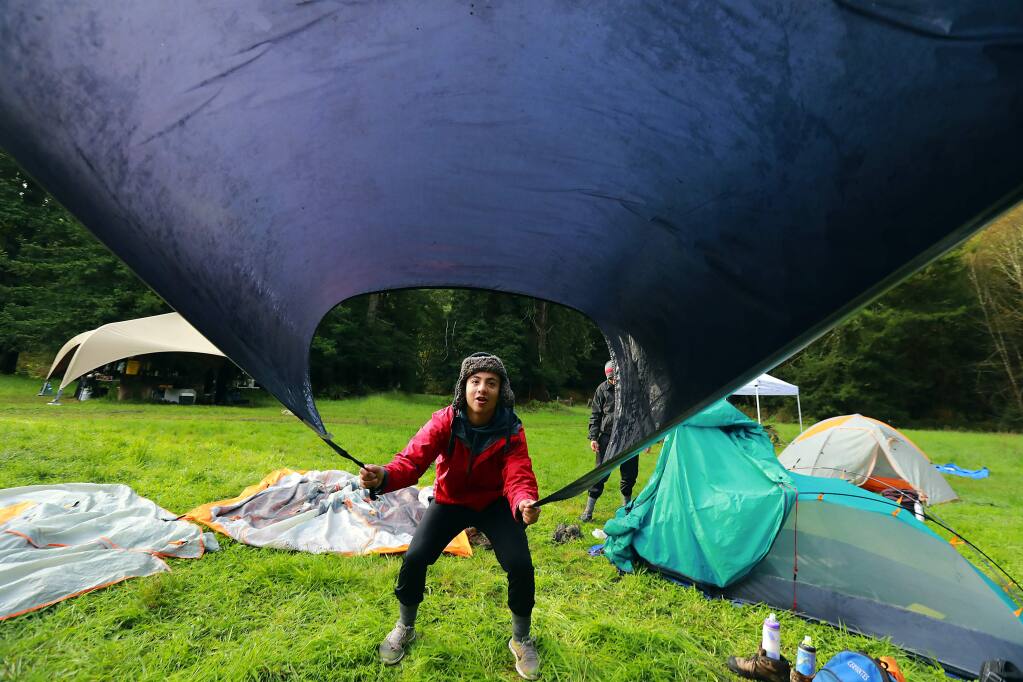 Jorge Cervantes shakes the dew from the tent rainfly before setting off to hike the last 5 miles of their 4 day trek to the ocean with the Inspired Forward program sponsored by LandPaths. (John Burgess/The Press Democrat)