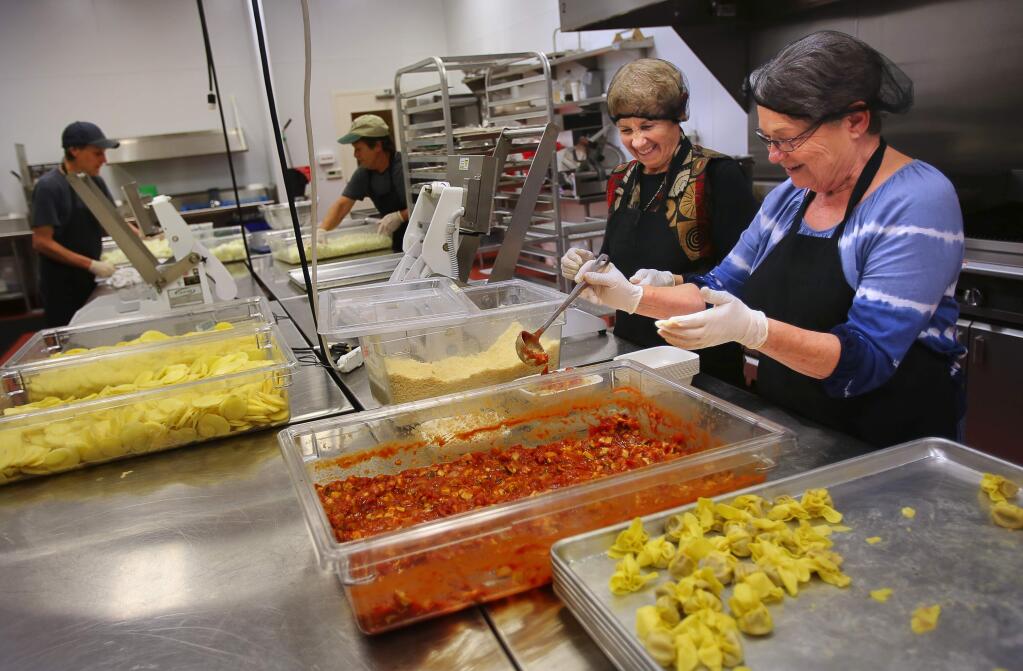 Judy Smith, right, and Jennifer Girvin pack vegeterian pasta meals at the Kitchen Collective in the Redwood Empire Food Bank in Santa Rosa on Friday, March 25, 2016. (Christopher Chung / The Press Democrat)