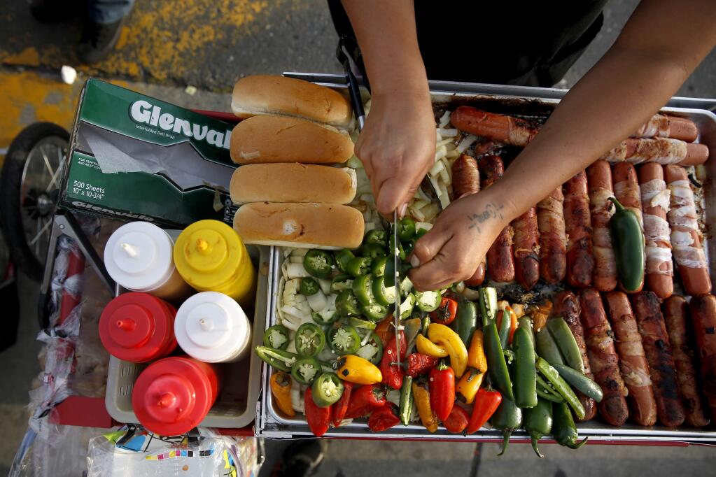 Dulce Gomez prepares bacon wrapped hot dogs to sell at Roseland's Cinco de Mayo celebration on Sebastopol Rd on Tuesday, May 5, 2015 in Santa Rosa, California . (BETH SCHLANKER/ The Press Democrat)