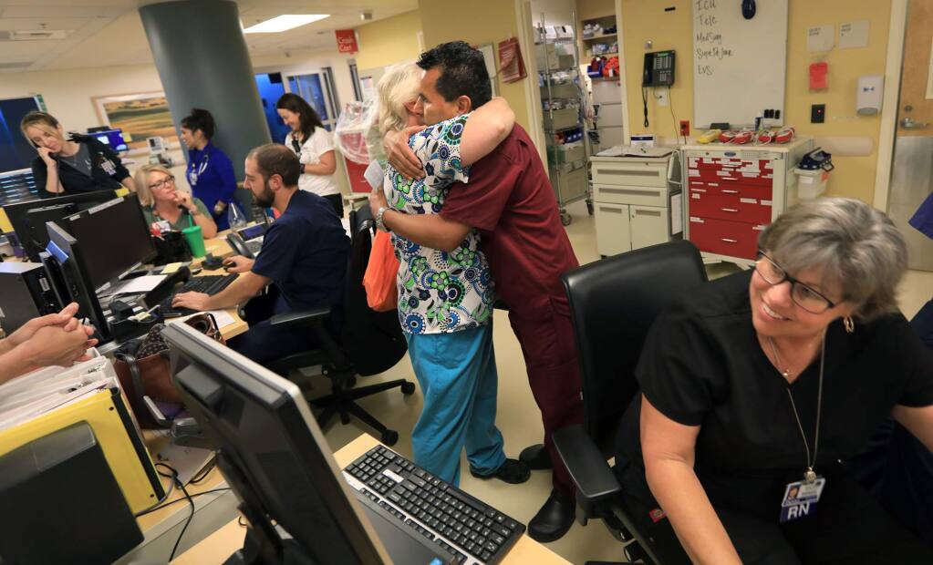 Crista Gatti and Israel Vigil embrace in an emergency room filled with Kaiser Medical Center nurses as the hospital opens Wednesday Oct. 25, 2017, since the Tubbs fire ravaged Santa Rosa and Kaiser was forced to evacuate. Gatti lost her home in Coffey Park, and Denise Parsons, bottom, lost her rental house in the same area. (Kent Porter / Press Democrat) 2017